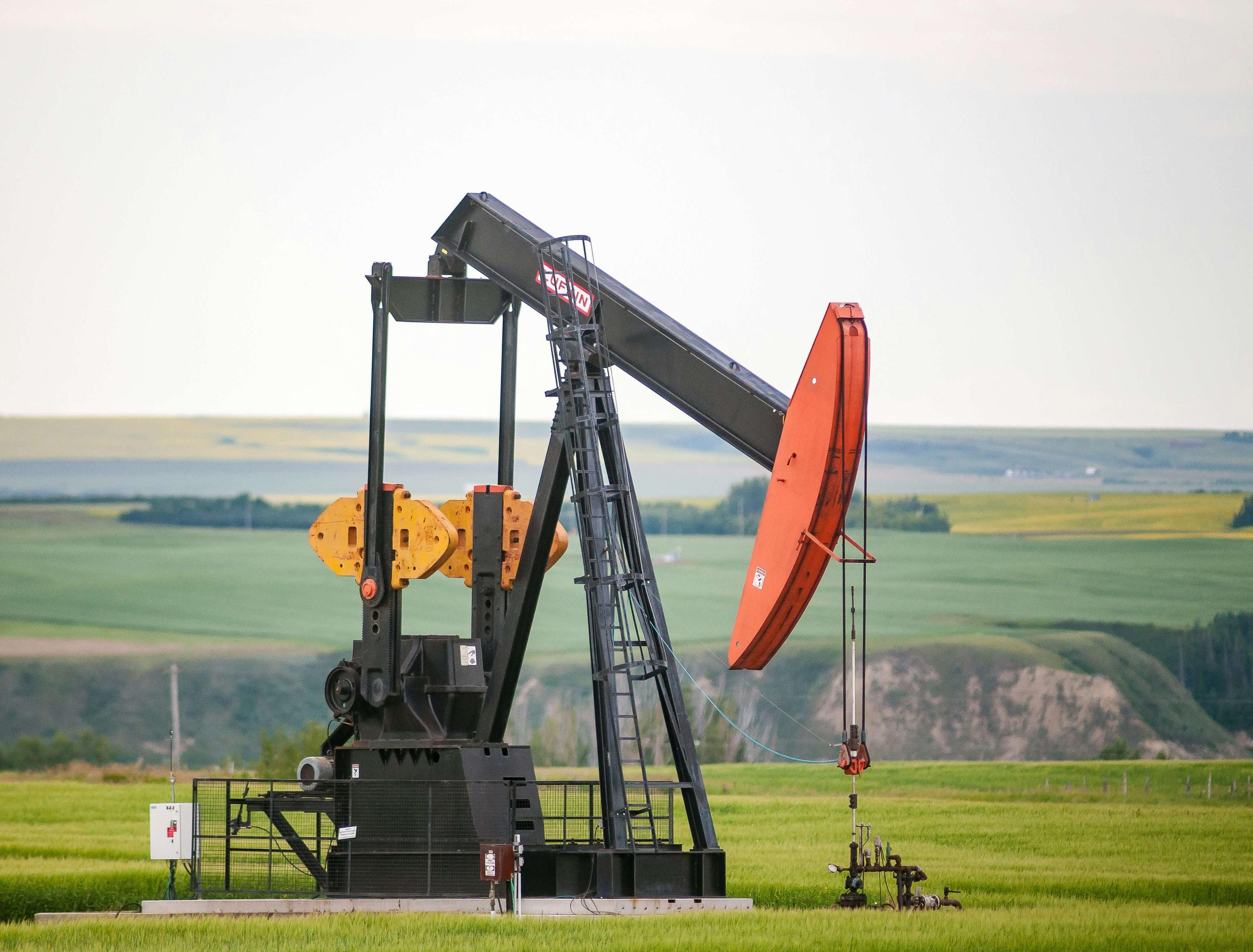 An oil pumpjack operating in a field, showcasing the ongoing extraction of valuable resources from the land.